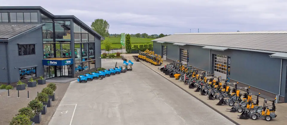 Het pand van Den Hartog Bouwmaterieel in Montfoort met een rij Messersi rupsdumpers en Giant wielladers